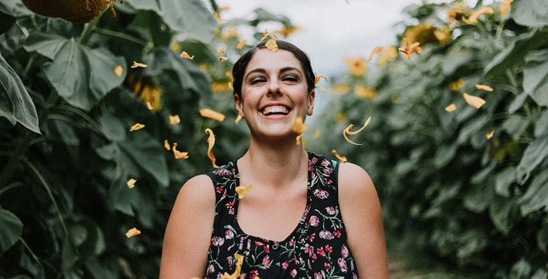 Woman in a field of green with yellow petals