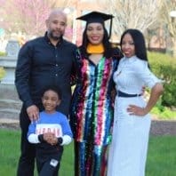 Family photo Carelicha D. in graduation gown with her husband and two kids