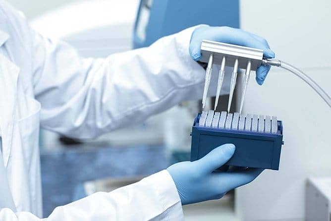 Scientist in gloves examining vials
