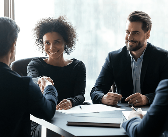 group sitting in office shaking hands and discussing paperwork