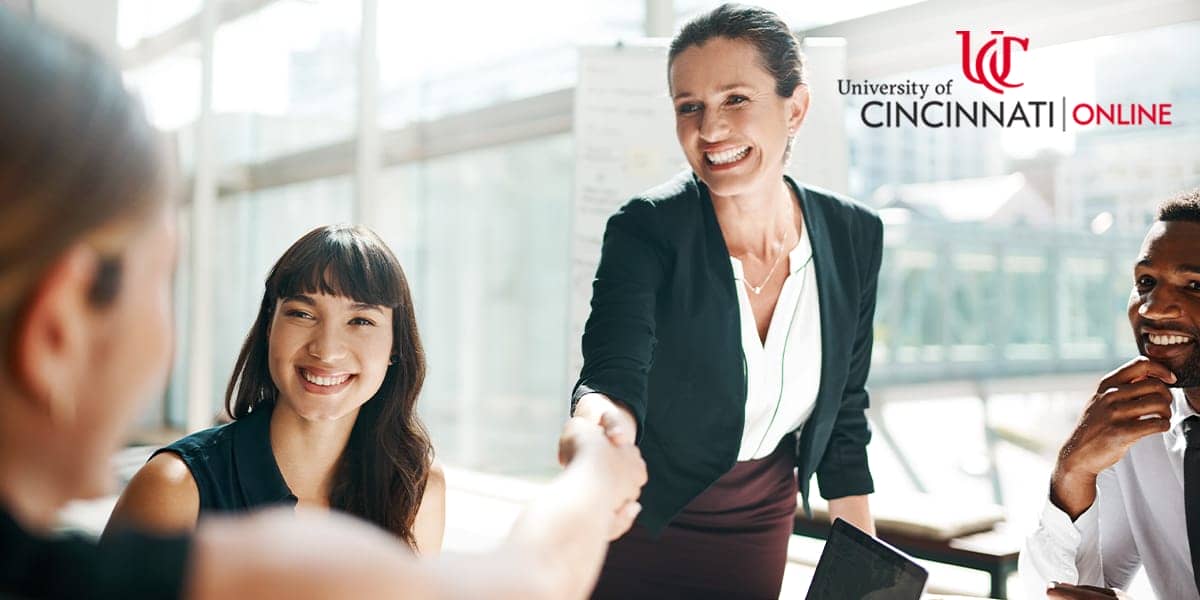 Image of MBA graduate shaking hands with other business professionals